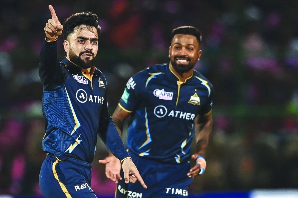 Gujarat Titans’ Rashid Khan (left) celebrates with Hardik Pandya after taking the wicket of Rajasthan Royals’ Ravichandran Ashwin (not pictured) during the IPL match in Jaipur on Friday. (AFP)