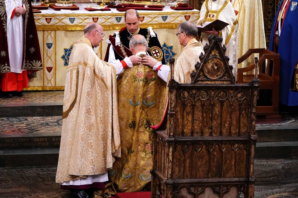 The Prince of Wales watches as a robe is put on King Charles III during his coronation ceremony. REUTERS