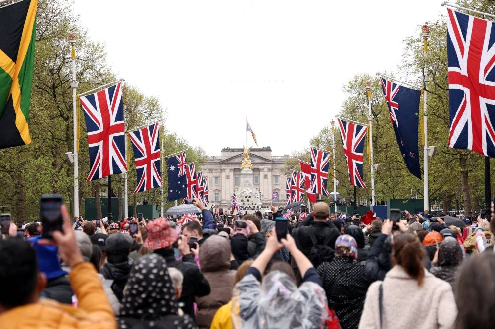 Well-wishers hold up their phones to take pictures of Buckingham Pala during the Coronation of King Charles III and Queen Camill. REUTERS