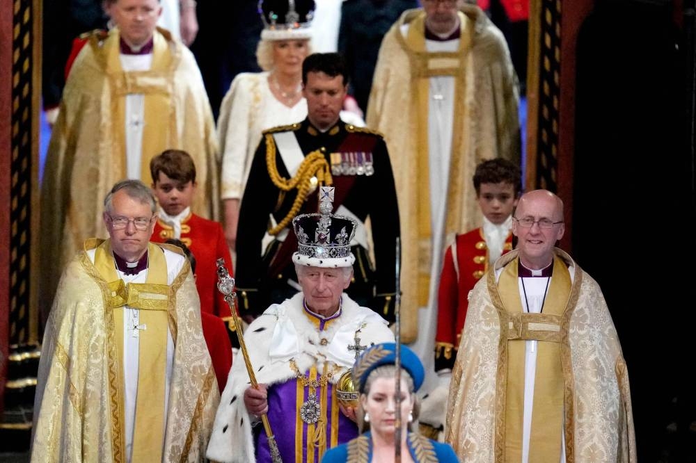 Britain's King Charles III wearing the Imperial state Crown, and Queen Camilla, wearing a modified version of Queen Mary's Crown leave Westminster Abbey after the Coronation Ceremonies in central London. AFP