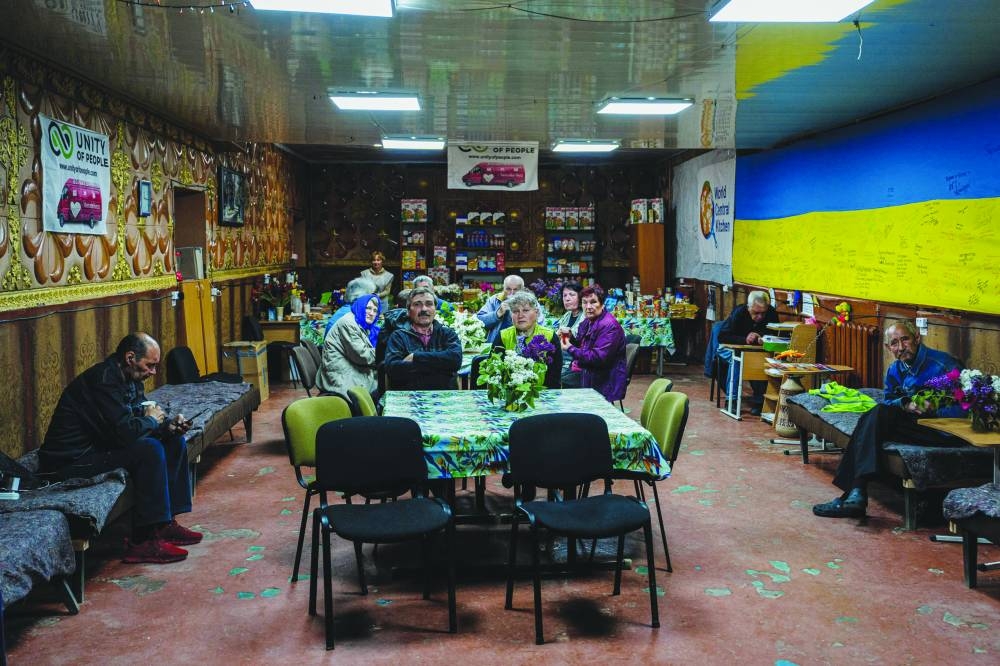 Local residents sit in a volunteer run shelter, providing access to laundry and bathroom facilities where they can warm up, charge their phones, drink hot tea and receive humanitarian aid in the town of Orikhiv, in the Zaporizhzhia region, yesterday. (AFP)