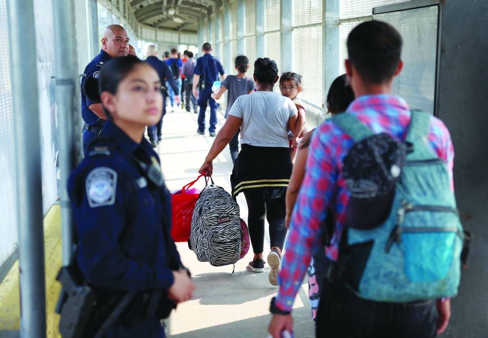 
Members of the United States Customs and Border Protection department watch as migrants cross the Matamoros-Brownsville International Bridge into the US after obtaining an appointment to legally enter the country, in Brownsville, Texas. 