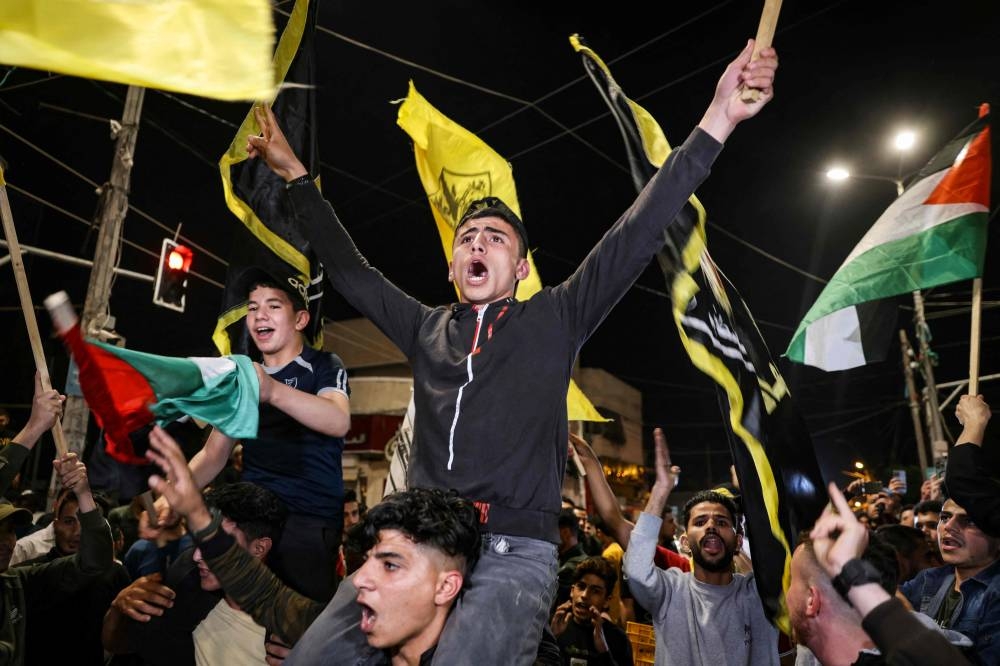 Palestinians and supporters of the Islamic Jihad group celebrate in the street after Palestinian factions and Israel reached a ceasefire agreement in Gaza City, yesterday.