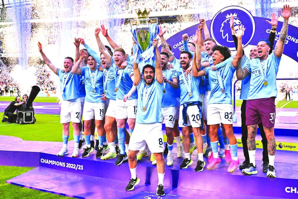 Manchester City’s midfielder Ilkay Gundogan lifts the trophy as his teammates celebrate winning the title at the presentation ceremony following the Premier League match against Chelsea in Manchester on Sunday. (AFP)