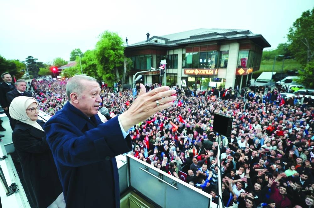 Turkish President Tayyip Erdogan, accompanied by his wife Emine Erdogan, addresses his supporters following early poll results for the second round of the presidential election in Istanbul, Sunday.