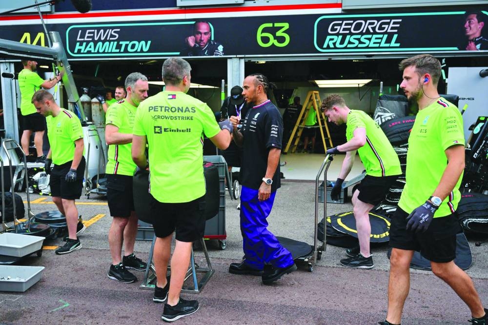 
Third-placed Alpine’s French driver Esteban Ocon celebrates with his trophy on the podium after the Formula One Monaco Grand Prix in Monaco on Sunday. RIGHT: Mercedes’ British driver Lewis Hamilton with team members in the pits after the race. (AFP)
 