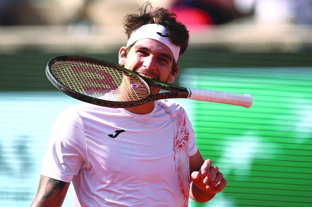 Brazil’s Thiago Seyboth Wild bites his racket during his match against Russia’s Daniil Medvedev on day three of French Open in Paris on Tuesday. Wild won 7-6(5), 6-7(6), 2-6, 6-3, 6-4. (AFP)