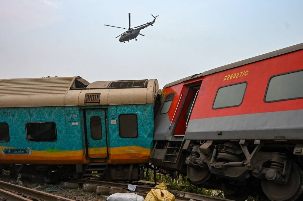 An army helicopter flies above the carriage wreckage of a three-train collision near Balasore, in India's eastern state of Odisha. DIBYANGSHU SARKAR / AFP