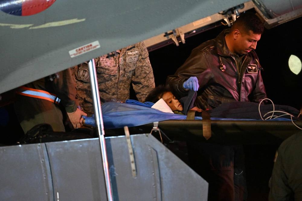 One of the four Indigenous children who were found alive after being lost for 40 days in the Colombian Amazon forest following a plane crash, is stretchered out of a plane upon landing at the CATAM military base in Bogota on June 10, 2023. Juan BARRETO / AFP