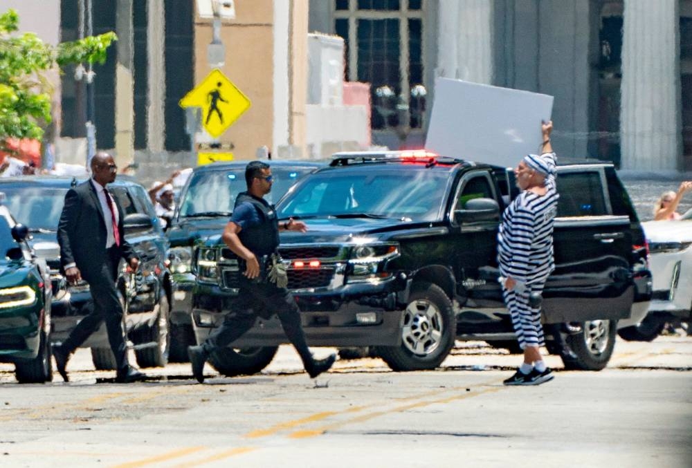 A man gestures as the motorcade of former US President Donald Trump arrives at the Wilkie D. Ferguson Jr. United States Courthouse, for Trump to appear at his arraignment on classified document charges, in Miami, Florida. Greg Lovett/TThe Palm Beach Post/USA TODAY NETWORK via REUTERS 