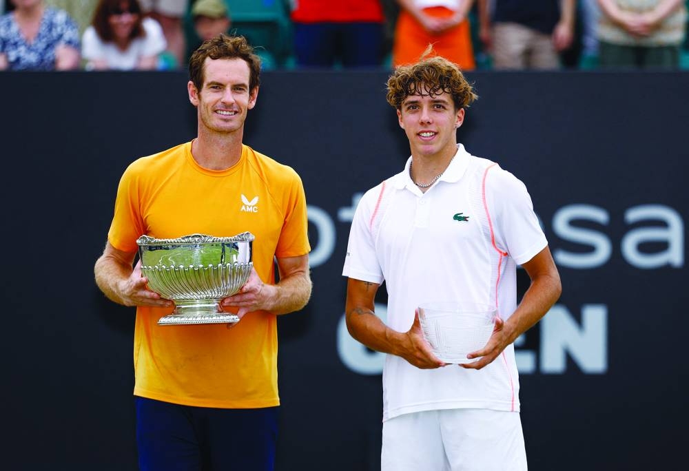 Britain’s Andy Murray poses with the trophy after winning the Nottingham Open alongside runner-up France’s Arthur Cazaux on Sunday. (Reuters)