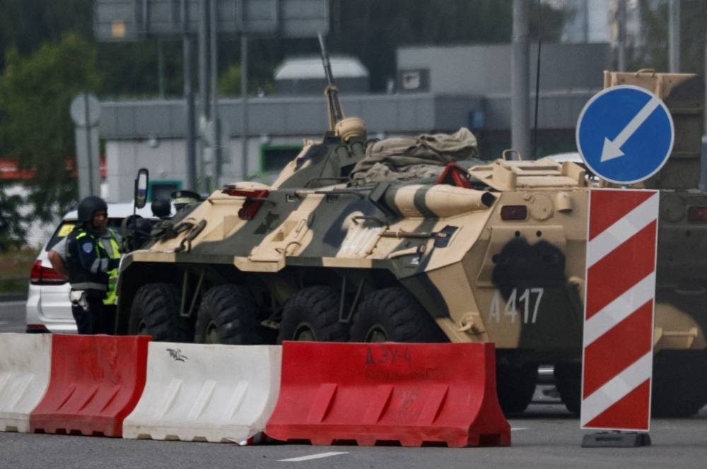A traffic police officer checks a car next to an armoured personnel carrier (APC) in Moscow, Russia.  REUTERS/Stringer