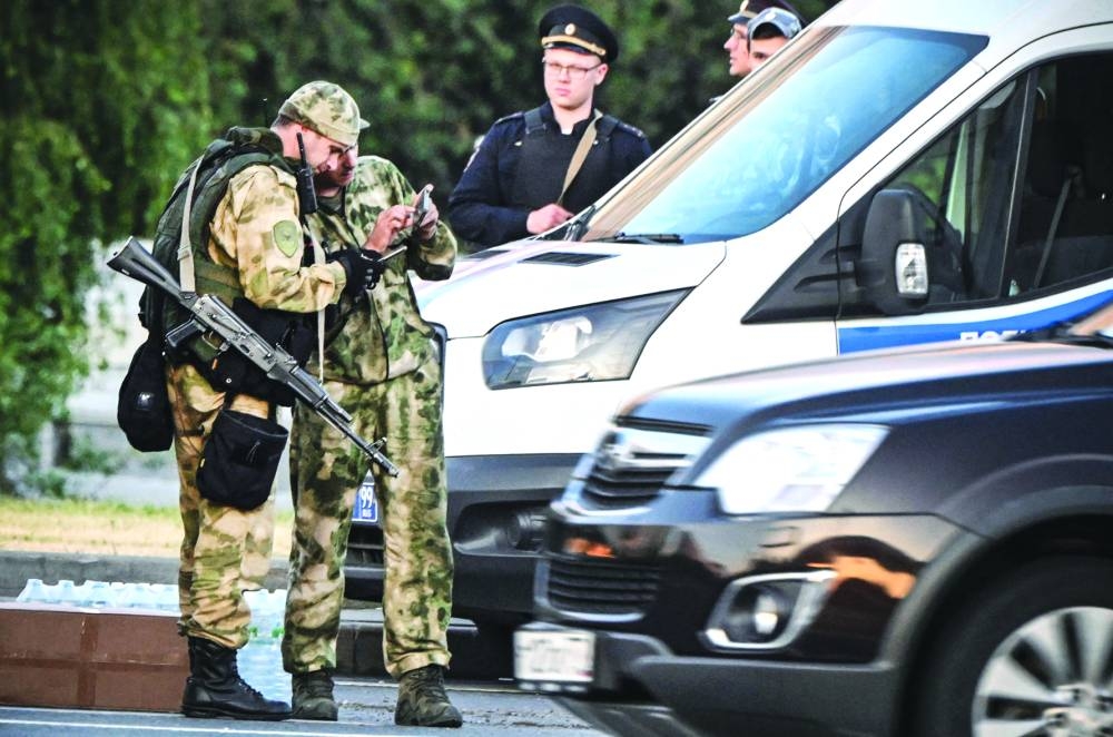 Russian soldiers and police officers stand an the edge of one of the a highways entering Moscow Saturday.