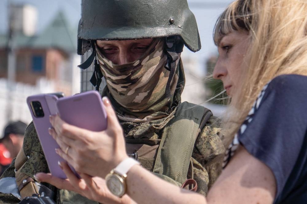 A woman shows her mobile phone as she speaks with a member of the Wagner group in the city of Rostov-on-Don, on June 24. Roman ROMOKHOV / AFP