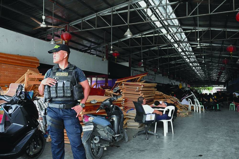A policeman stands guard inside a compound, where police raided buildings in Metro Manila on Tuesday.