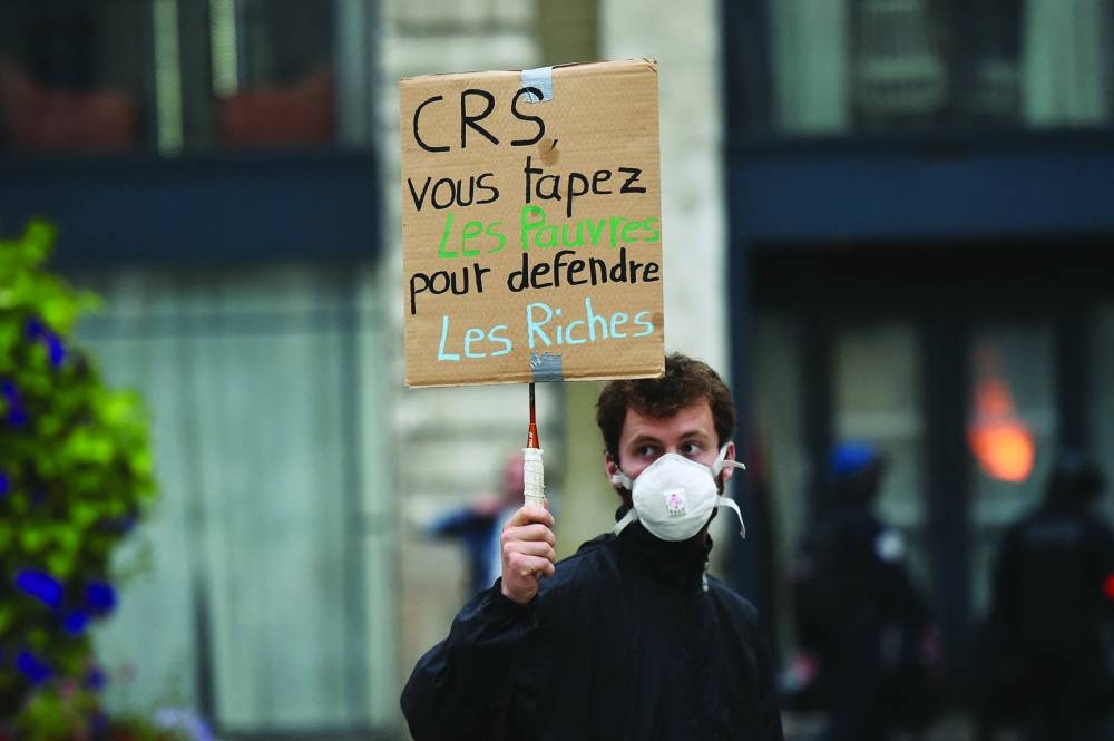 
A man holds a placard that reads ‘CRS (police) you bash the poor to defend the rich’, during a protest in Nantes. 