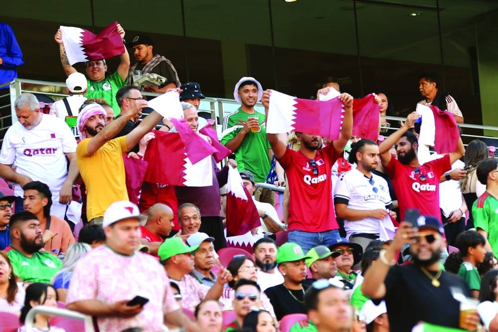 Al Annabi fans draped in maroon jerseys cheer their team during the match.