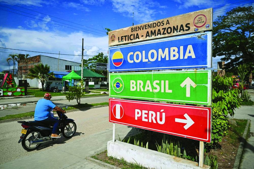 
A man rides a motorcycle passing by road signs in Leticia, Colombia. 