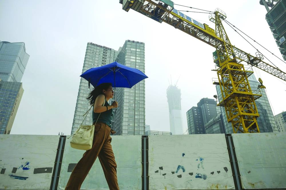 
A woman holding an umbrella walks past a construction site in Beijing. China’s real estate crisis is stifling a recovery in the world’s second-largest economy, fuelling expectations for the government to take more steps to revive demand. 