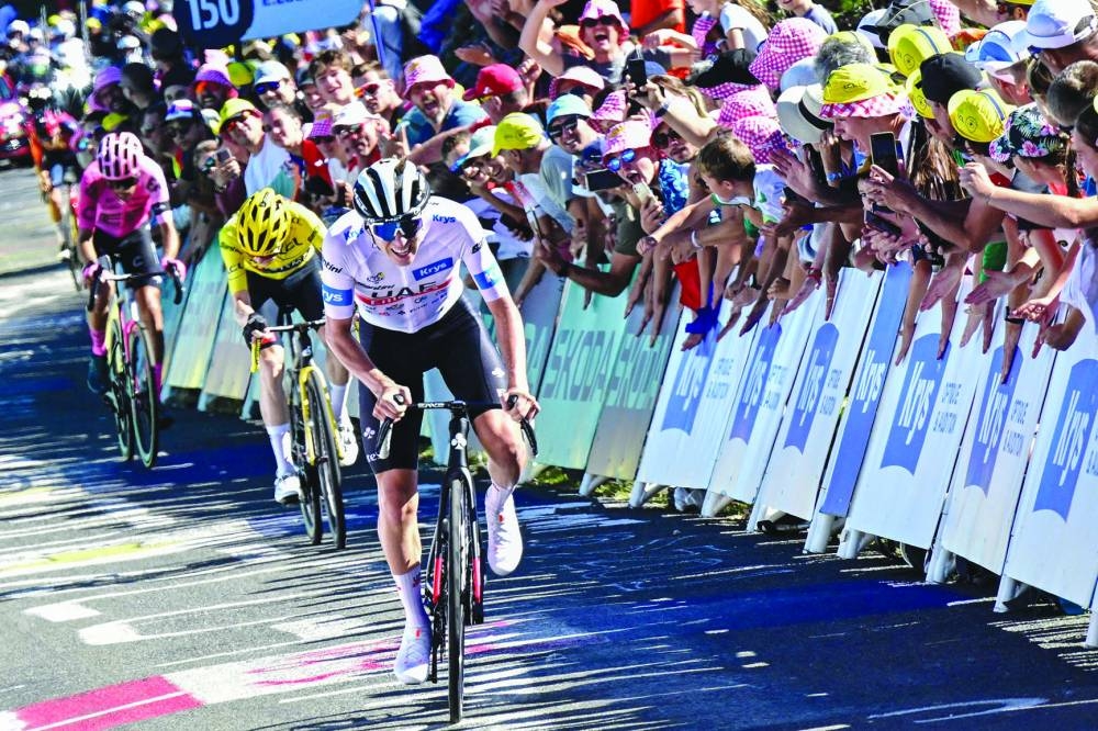 UAE Team Emirates’ Slovenian rider Tadej Pogacar - wearing the best young rider’s white jersey - cycles in the final ascent of Col du Grand Combier in the last few kilometres of the 13th stage of the 110th edition of the Tour de France cycling race, covering a distance of 138kms between Chatillon-sur-Chalaronne in central-eastern France and Grand Colombier, in the Jura mountains in Eastern France, yesterday. Right: Jumbo-Visma’s Danish rider Jonas Vingegaard wearing the overall leader’s yellow jersey cycles to the finish line. (AFP)