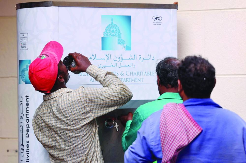 Workers line up in front of a water distributor on a hot summer day in Dubai.