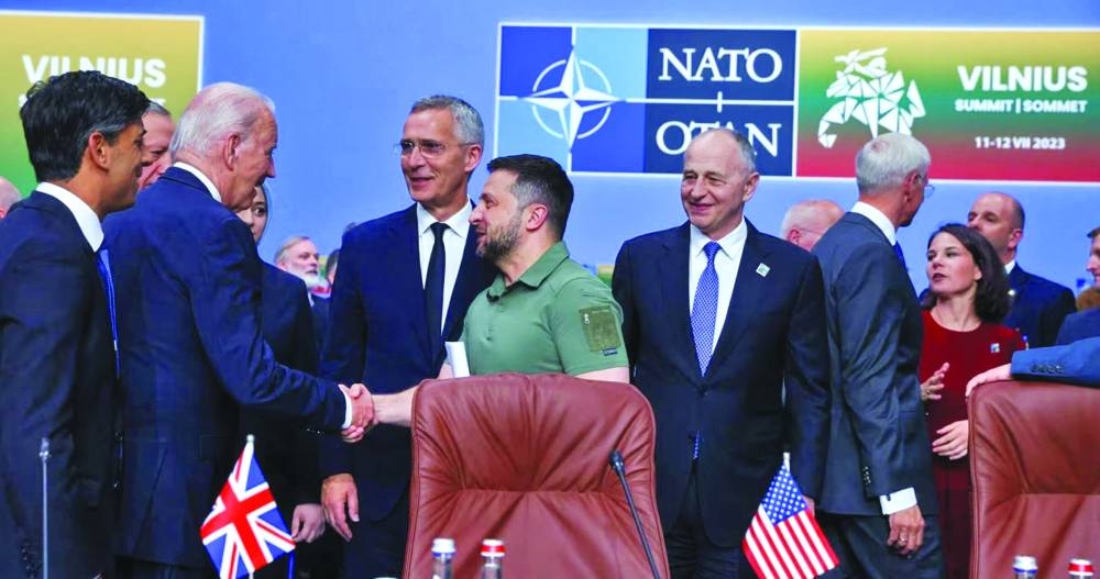 
Ukraine President Volodymyr Zelensky shaking hands with US President Joe Biden watched on by other world leaders at the Nato summit in Vilnius on Wednesday.  Right: Zelensky with his wife Olena Zelenska arrive to attend a dinner hosted by the Lithuanian president (Reuters) 