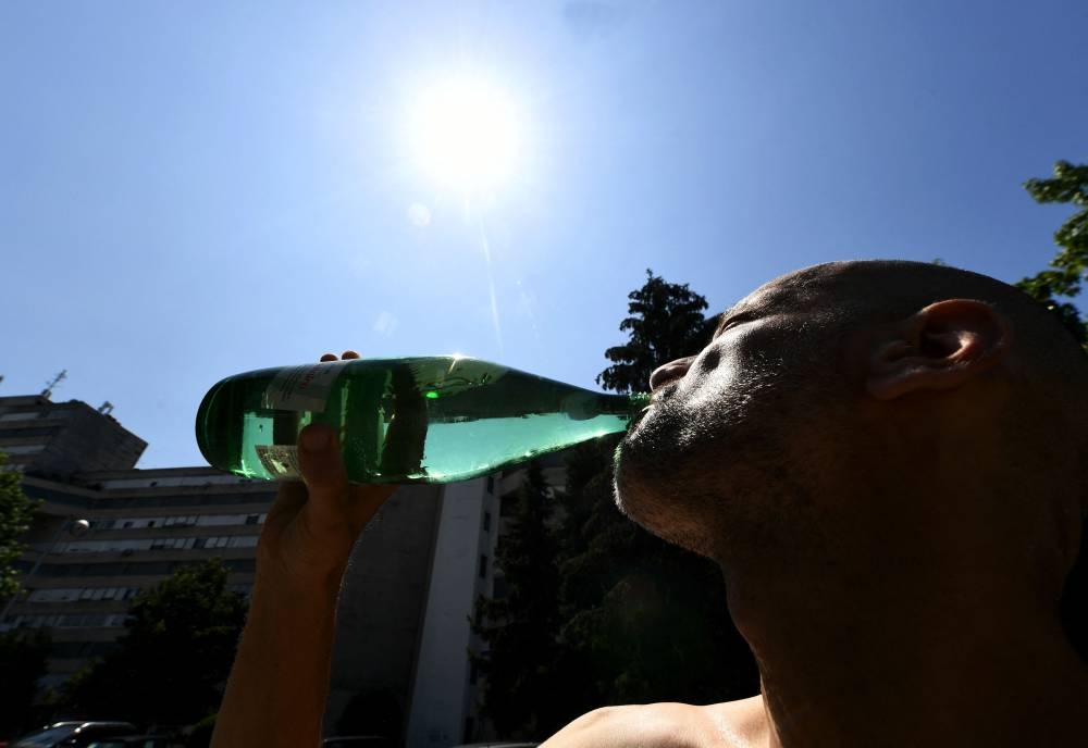A man drinks water from a bottle  in a building's parking lot in Zagreb on July 17, during a heatwave in Croatia. Denis LOVROVIC / AFP