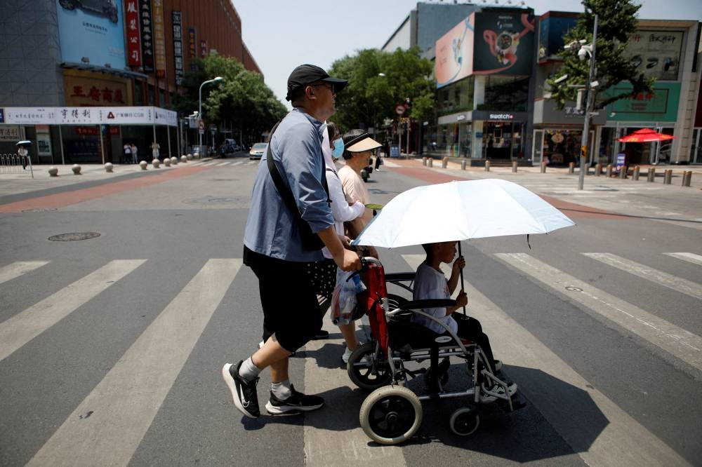 Pedestrians cross a road on a hot day amid an orange alert for heatwave, in Beijing, China June 16. REUTERS/Florence Lo/File Photo