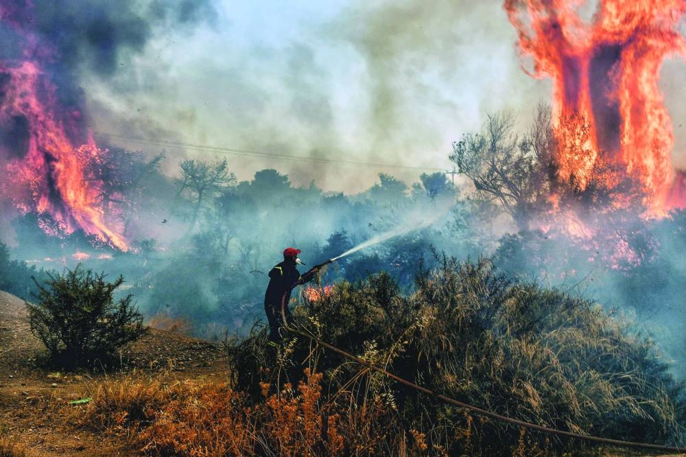 A fireman douses flames on a wildfire at Panorama settlement near Agioi Theodori, some 70km west of Athens, yesterday. (AFP)

