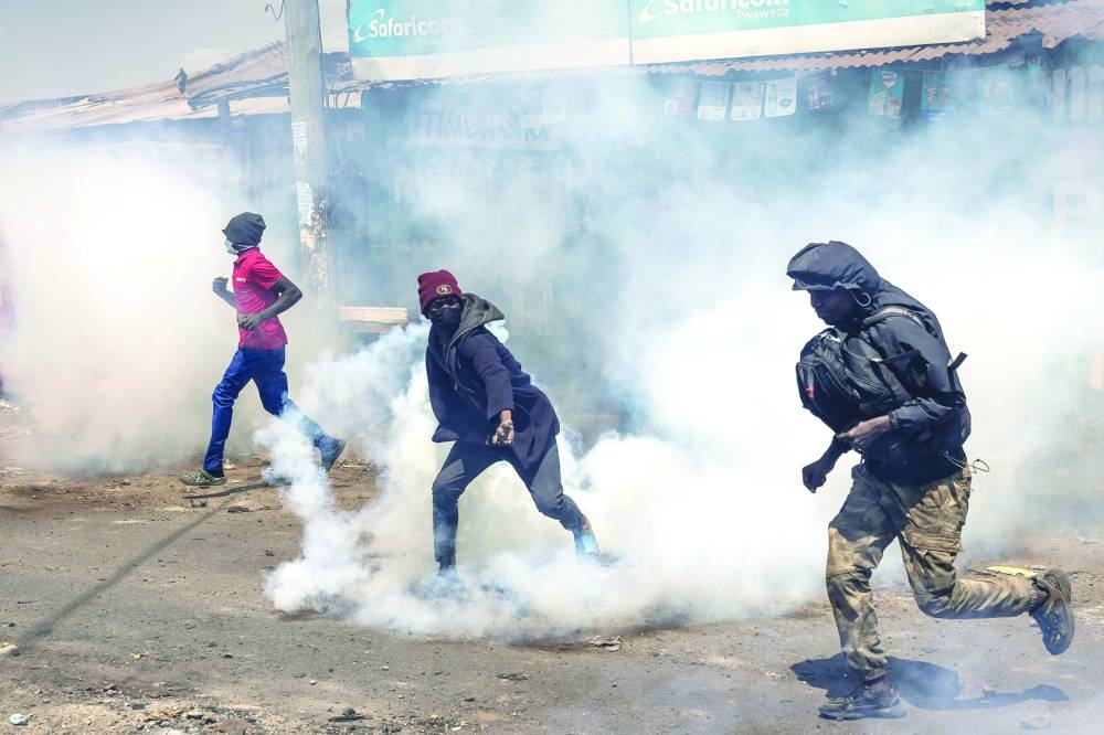 
An opposition supporter grabs a tear gas canister fired by anti-riot police as others take cover during clashes with Kenya Police Officers in Nairobi, yesterday. 