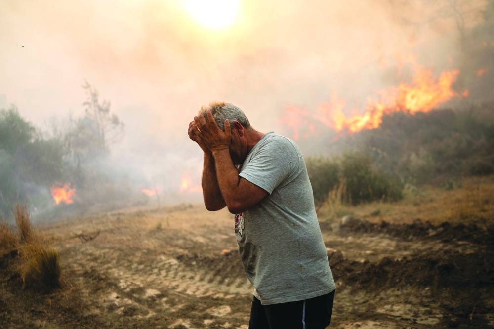 
A man reacts as a fire burns into the village of Gennadi on the Greek Aegean island of Rhodes. (AFP) 