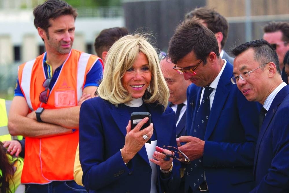 French First Lady, Brigitte Macron (left), Director of the French zoo parc of Beauval, Rodolphe Delord (second right) and Chinese ambassador Lu Shaye react near the airplane carrying giant panda, Yuan Meng (seen through a hole in its transportation box) before boarding a plane at the Roissy-Charles-de-Gaulle airport on Tuesday. (AFP)