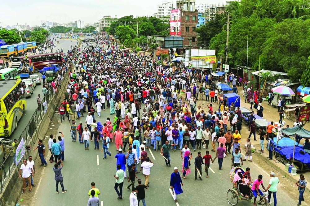 
Smoke rises as the supporters of the Bangladesh Nationalist Party (BNP) set a bus on fire in Shonir Akhra area while staging sit-in rallies on the main entry points of the capital Dhaka, Bangladesh, yesterday. Right: Bangladesh Nationalist Party (BNP) activists block a highway entering Bangladesh’s capital during a protest demanding the resignation of Prime Minister Sheikh Hasina and a general election under a neutral caretaker government, in Dhaka. 