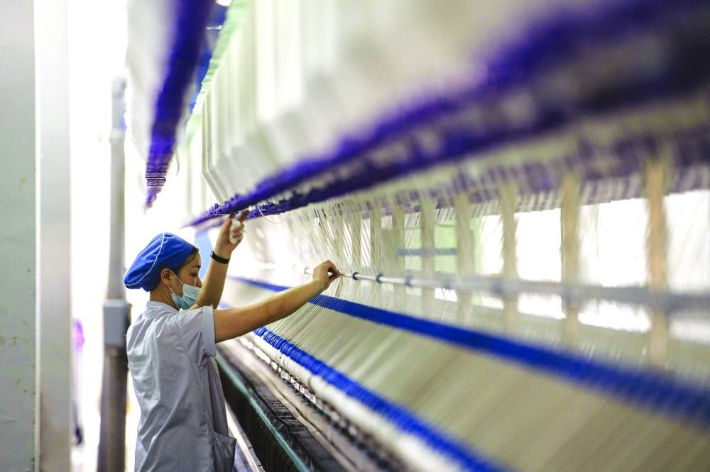 
A worker stands in front of a machine on a yarn production line at the Fujian Strait Textile Technology factory in Putian. China’s economic activity lost more steam in July with manufacturing contracting again and the services sector weakening, as Beijing promises small measures of support to boost consumption. 