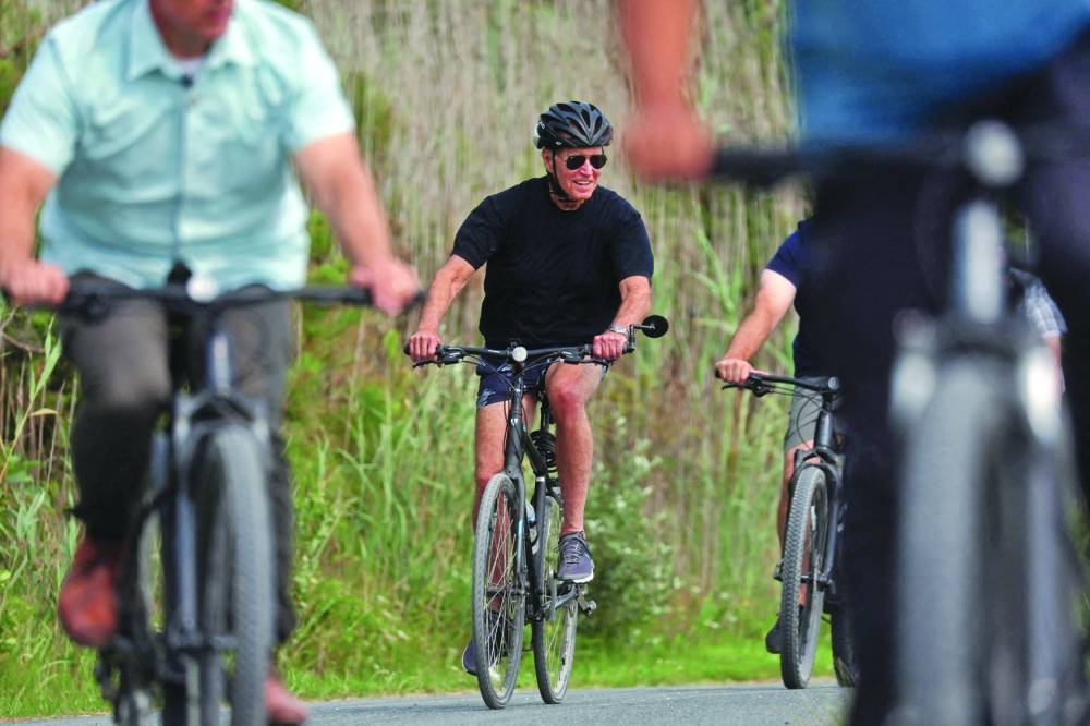 Left: Biden rides his bike down a path accompanied by Secret Service agents in Gordons Pond State Park in Rehoboth Beach, Delaware.