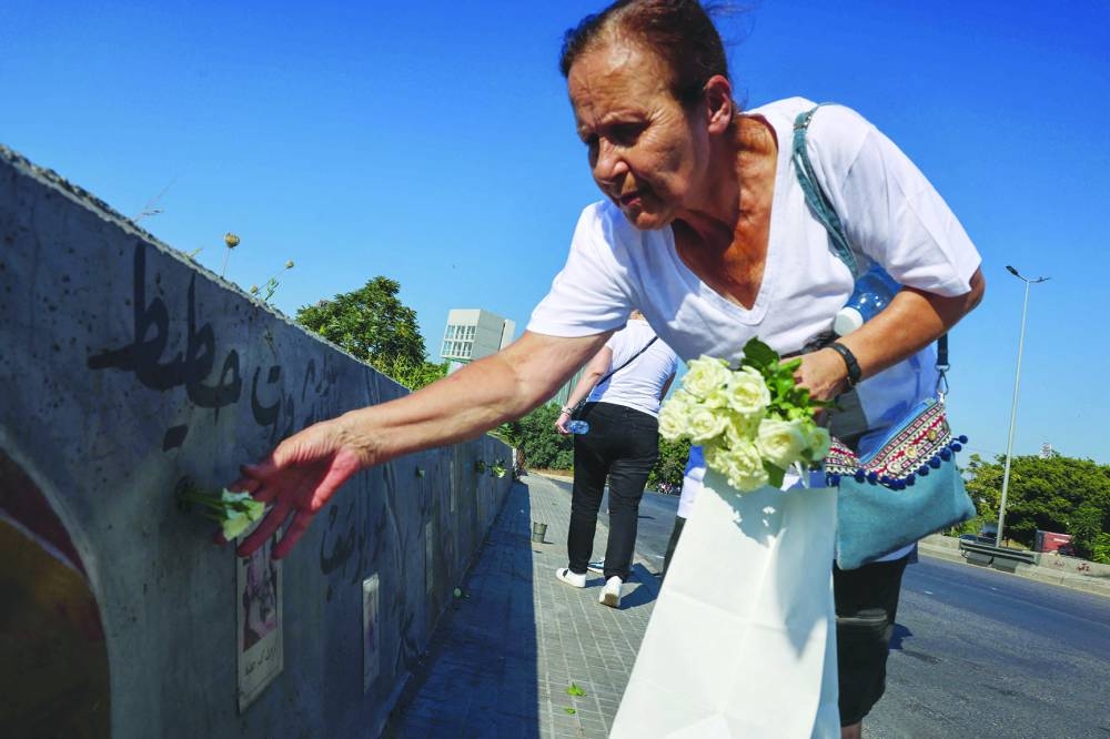 
A woman places roses in a memorial wall for victims. 