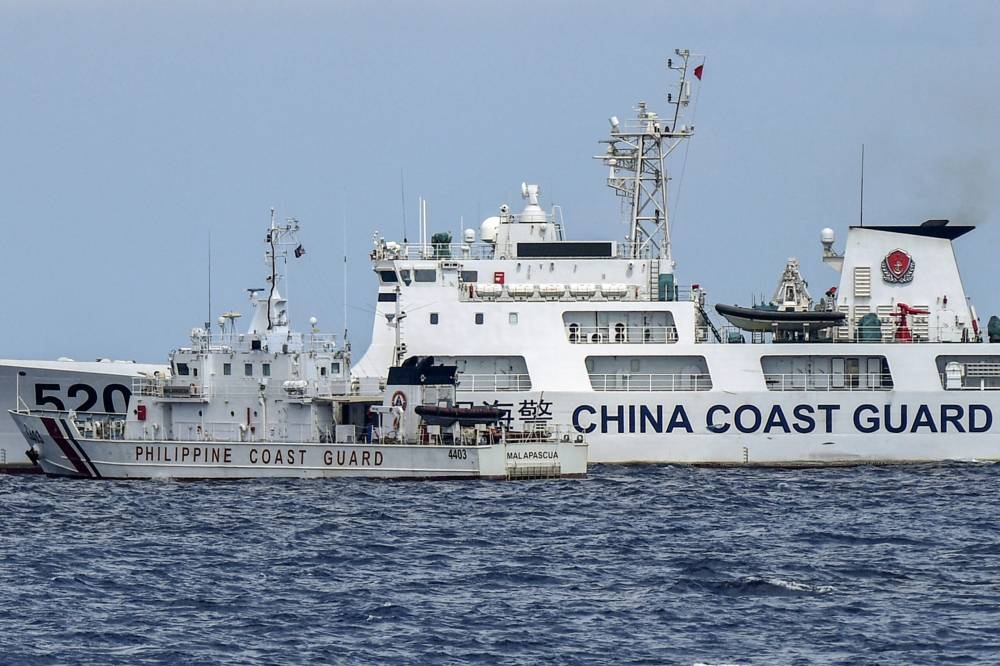 This photo taken on April 23, 2023 shows the Philippine coast guard vessel BRP Malapascua (front) manoeuvering as a Chinese coast guard ship cuts its path at Second Thomas Shoal in the Spratly Islands in the disputed South China Sea. - AFP was one of several media outlets invited to join two Philippine Coast Guard boats on a 1,670-kilometre (1,040-mile) patrol of the South China Sea, visiting a dozen islands and reefs. Beijing claims sovereignty over almost the entire South China Sea, including the Spratly Islands, ignoring an international ruling that the assertion has no legal basis. (Photo by Ted ALJIBE / AFP) / TO GO WITH AFP SPECIAL REPORT BY CECIL MORELLA - To go with AFP SPECIAL REPORT by Cecil MORELLA