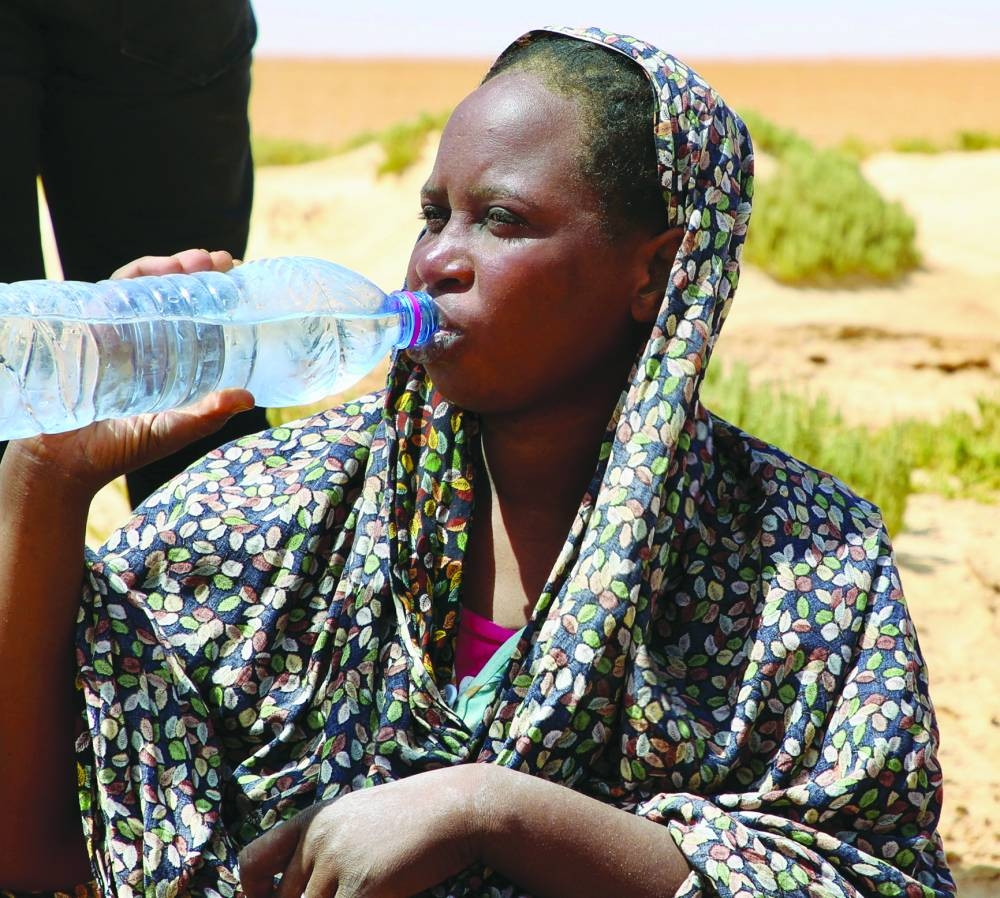 
Tafaul Omar, a pregnant 26-year-old nurse from Sudan, drinks water as she is stranded in the desert on the Libyan-Tunisian border, near Al-Assah. 