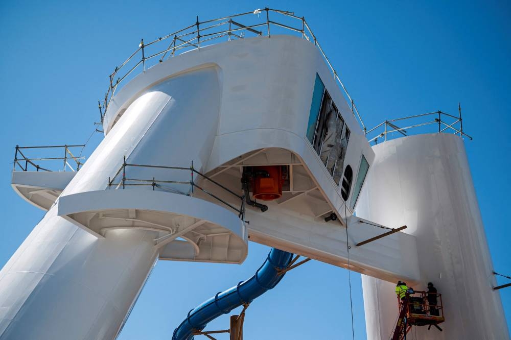 Workers are seen on a lifting platform working on the exterior of the Royal Caribbean's new ship 'Icon of the Seas' currently under construction at the Turku shipyard in Finland's southwest coast on May 30, 2023. AFP