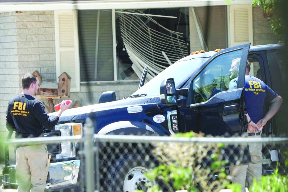 
With a broken window in the background, FBI agents process the home of Craig Robertson who was shot and killed by the FBI in a raid on his home last morning in Provo, Utah. (AFP) 