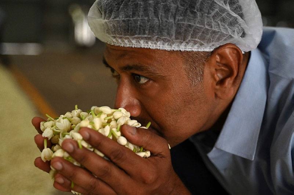 (File photo) Raja Palaniswamy, a director at the Jasmine Concrete Exports Private Limited, smells Jasmine flowers at his factory in Dindigul. (AFP)