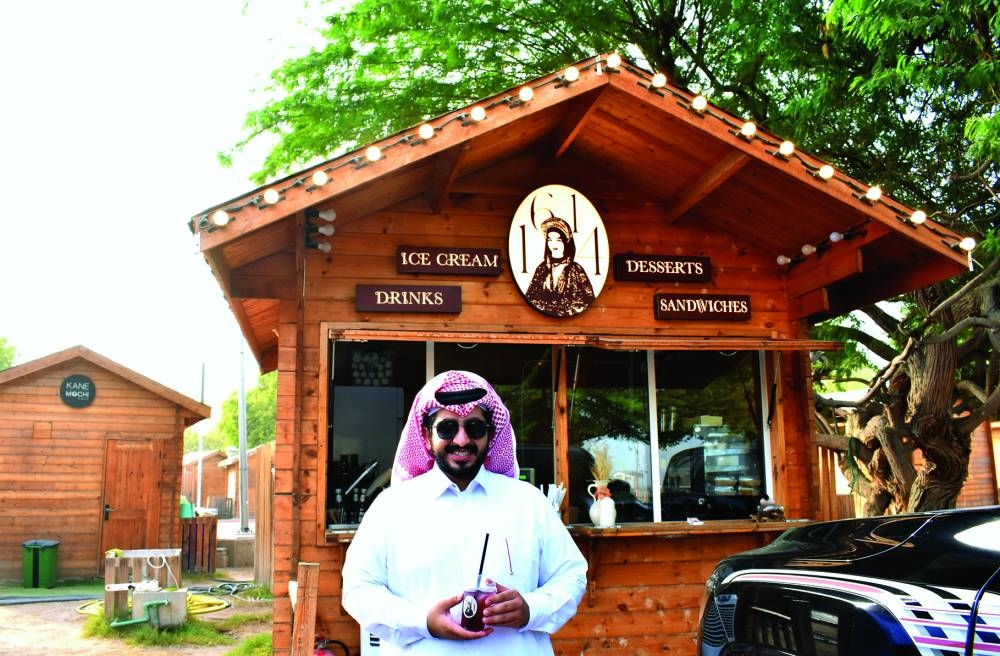 Jassim Ahmed al-Shafai in front of the 1614 Coffee Lounge branch at Katara Tasty Street on Thursday as he showcases its latest drink. PICTURE: Thajudheen and 1614 Instagram screengrabs.