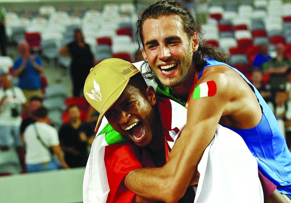 Gold medallist Italy's Gianmarco Tamberi celebrates winning the final alongside bronze medallist Qatar's Mutaz Essa Barshim. REUTERS