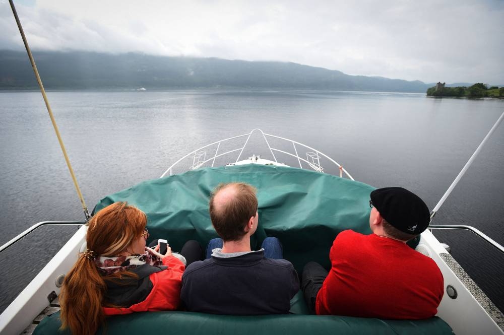 Tourists take a cruise aboard the 'Nessie Hunter' boat on Loch Ness in the Scottish Highlands on June 10, 2018. AFP