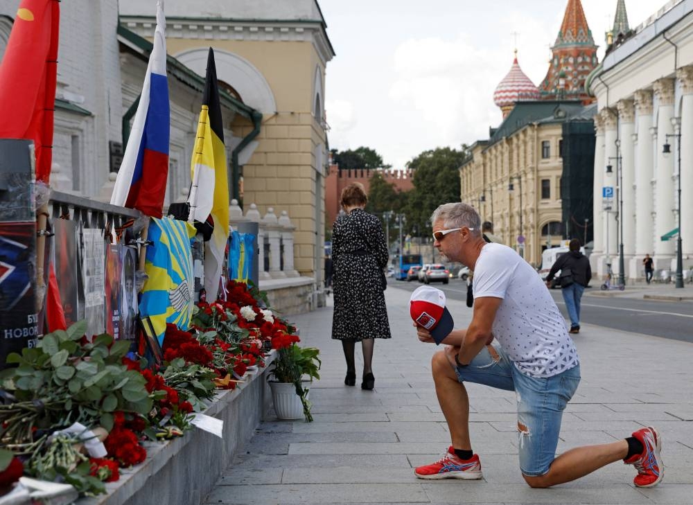 A man takes a knee in front of a makeshift memorial set up after the presumed death of Yevgeny Prigozhin, head of the Wagner mercenary group, in a plane crash, in Moscow, Russia on August 25. REUTERS