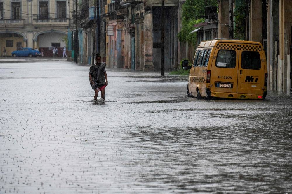 A man walks through a flooded street in Havana during the passage of tropical storm Idalia. AFP