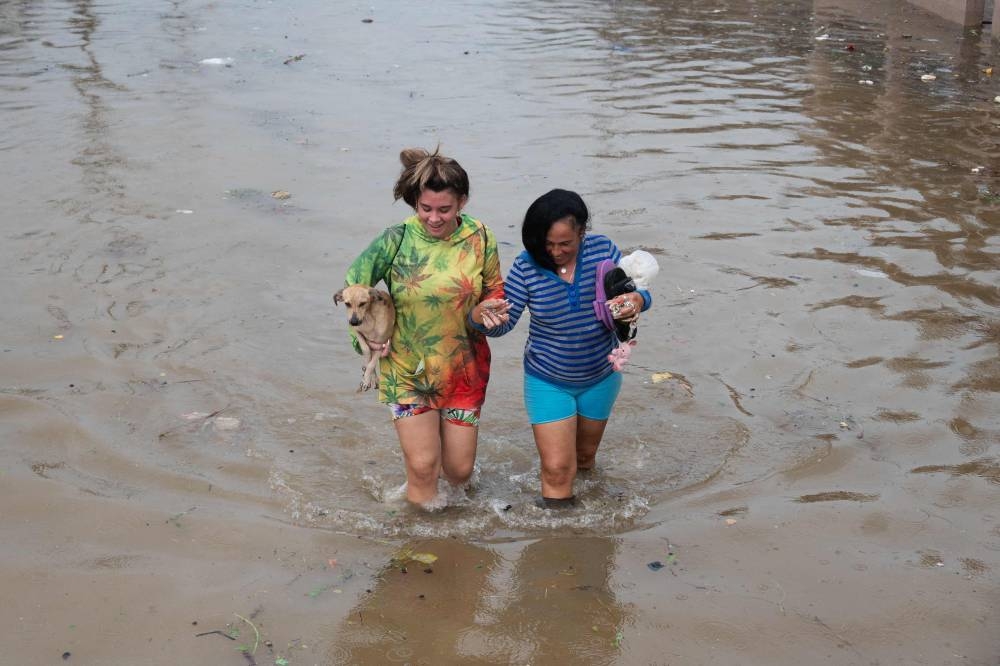 People walk through a flooded street in Batabano, Mayabeque province, Cuba during the passage of tropical storm Idalia. AFP