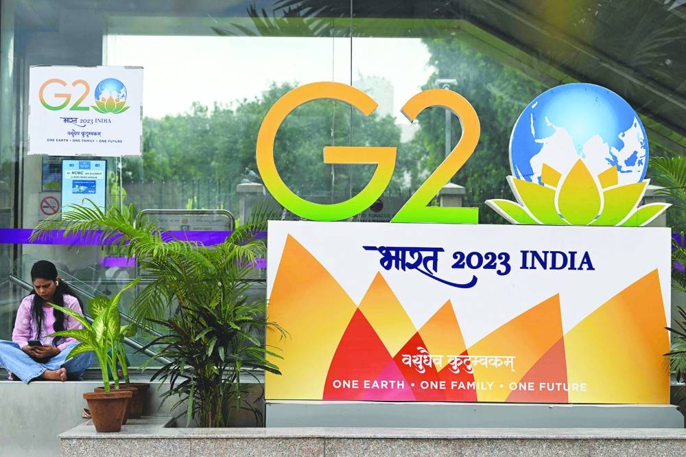 
A woman sits near a G20 summit logo installed along a street in New Delhi yesterday. ( AFP) 