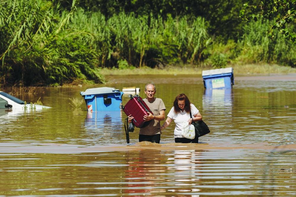 Locals walk away from a flooded area while carrying their belongings, in the aftermath of Storm Daniel in central Greece, in Larissa, Greece, on Friday.