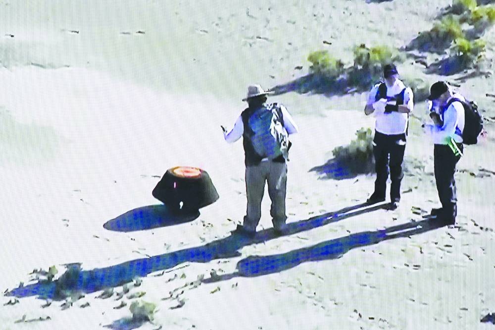 This shot off a Nasa live feed shows safety team members prepare the Osiris-Rex asteroid sample return craft sitting in the Utah desert  yesterday. 